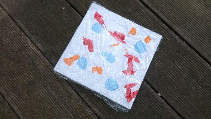 Ein bunter, schmutzfreier Malblock liegt auf einem Holzdeck, bereit f&uuml;r kreativen Malspa&szlig; f&uuml;r Babys.