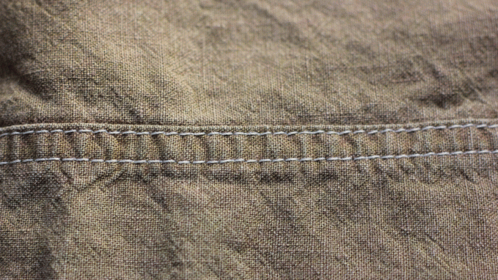 Ein Stoffst&uuml;ck mit einer feinen, grauen Naht liegt auf einem neutralen Hintergrund, ideal f&uuml;r Textilrecycling f&uuml;rs Geschirr.