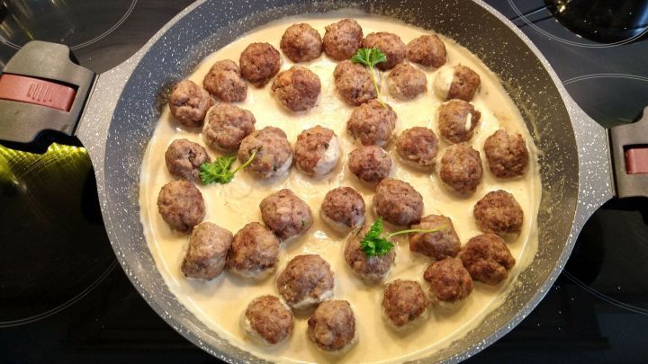In einer Pfanne kochen saftige Fleischb&auml;llchen in raffinierter Mandelso&szlig;e, umgeben von einer cremigen Sauce.