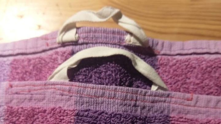 Ein Handtuch mit Aufh&auml;ngeschlaufen h&auml;ngt beidseitig auf einer Holzoberfl&auml;che, bereit zur Nutzung.