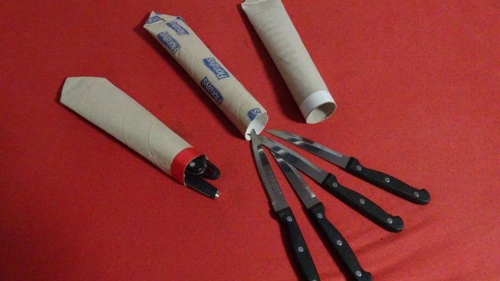 Ein Besteckk&ouml;cher &ouml;ffnet sich, um mehrere schwarze Messer auf einem roten Untergrund zu pr&auml;sentieren, ideal f&uuml;rs Camping.