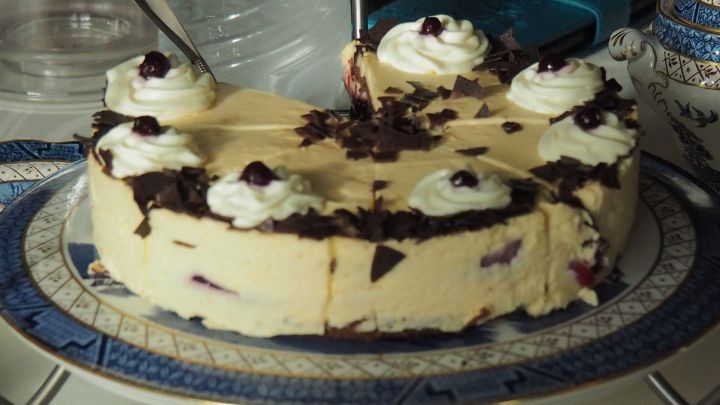 Die Schwarzw&auml;lder Kirschtorte steht auf einem dekorativen Teller, umgeben von einer festlichen Tischdekoration.