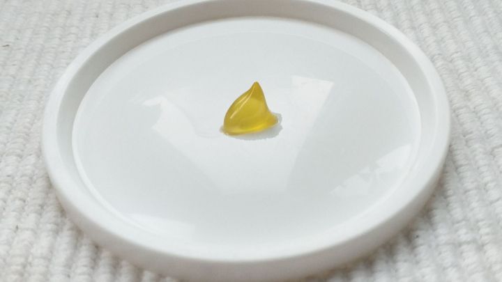 Ein kleiner gelbes Heil&ouml;lst&uuml;ckchen liegt in einer wei&szlig;en Schale auf einem weichen, hellen Untergrund.