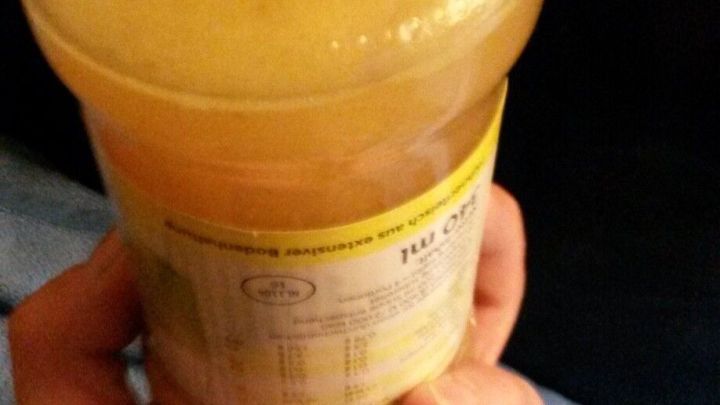 Ein Konservenglas mit Drehverschluss wird in einer Hand gehalten, w&auml;hrend die andere Hand fast bereit ist, es zu &ouml;ffnen.