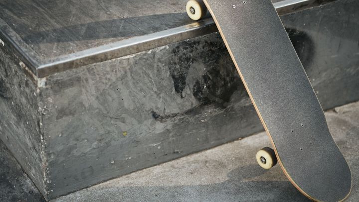 Ein Skateboard liegt auf einer Kante, w&auml;hrend ein Rider sich auf die Landung vorbereitet, um Tricks zu zeigen.