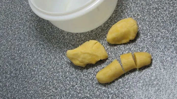 Den Teig zu Strängen rollen - “sanft“, sonst bröselt alles wieder auseinander. In Portionen schneiden (ergibt 12 Stück) und kugelig formen (Größe zwischen Marzipankartoffel und Tischtennisball).