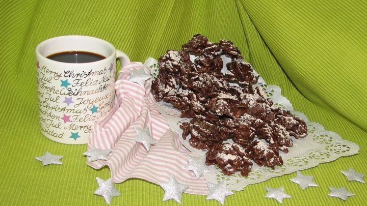 Eine Tasse Tee mit Schuss steht neben einem Haufen Schokocrossies auf einer Spitzendecke, umgeben von Sternen.