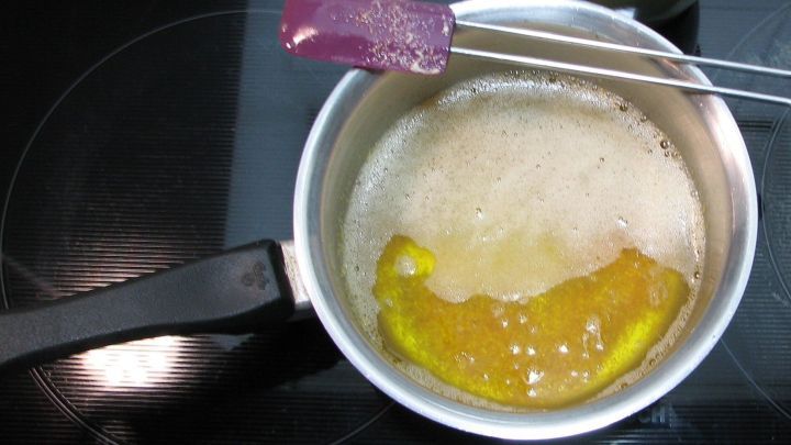 In einem Topf sch&auml;umt eine Mischung aus N&uuml;ssen und &Ouml;l, w&auml;hrend ein Spatel r&uuml;hrt; der Herd ist sichtbar.