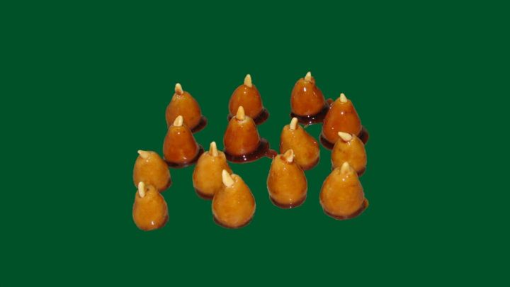 Kandierte Pinienzapfen liegen gruppiert auf einem gr&uuml;nen Hintergrund, gl&auml;nzend und appetitlich in ihrer s&uuml;&szlig;en Glasur.