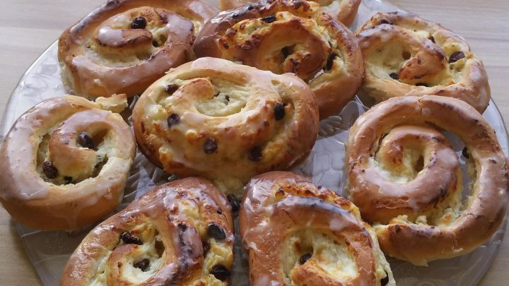 Zarte Quark-Pudding-Schnecken liegen auf einem Glas-Teller und warten auf den Genuss in einer gem&uuml;tlichen K&uuml;che.