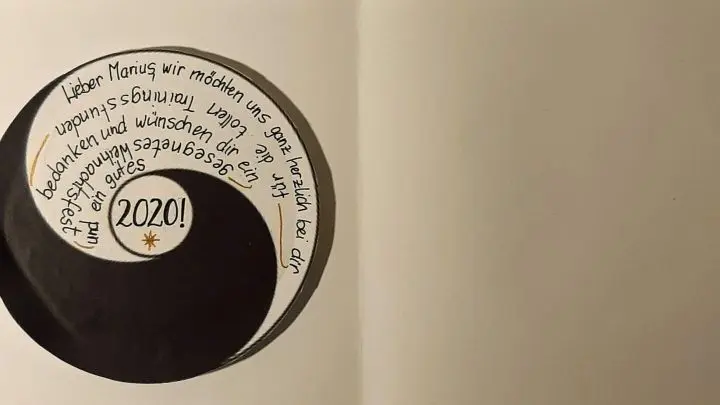 Das fertig beschriebene Yin-Yang-Zeichen mit den Weihnachtsw&uuml;nschen wird auf die linke Seite der Klappkarte geklebt.