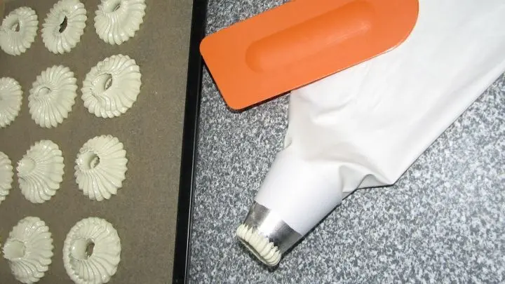 Die Adventskränze werden mit einem Durchmesser von ca. 6 cm auf ein mit Backpapier ausgelegtes Backblech gespritzt.