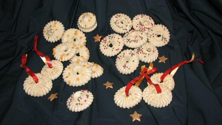 Weihnachtliche Adventskr&auml;nze liegen auf einem dunklen Hintergrund, umgeben von goldenen Sternen und roten B&auml;ndern.