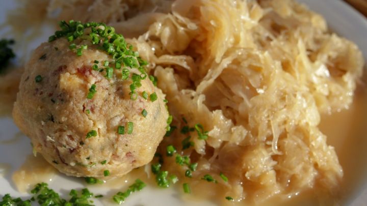 Ein Teller mit Sauerkraut schlesische Art, serviert mit einer fleischigen Kl&ouml;&szlig;e, garniert mit Schnittlauch.