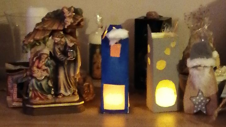 Auf einem Tisch stehen kreative Windlichter aus Tetrapaks, die sanft leuchten und eine festliche Stimmung verbreiten.