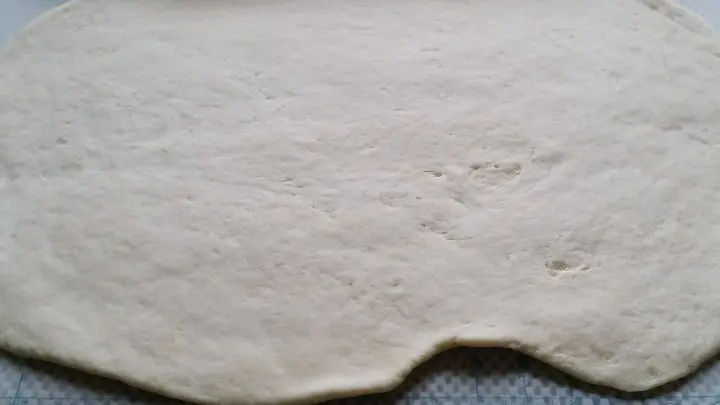 Der Teig f&uuml;r die Puddingschnecken wird auf der mit Mehl best&auml;ubten Arbeitsplatte mit einem Nudelholz d&uuml;nn ausgewellt.