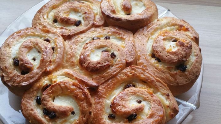 Auf einem Teller liegen frisch gebackene Puddingschnecken, die appetitlich und goldbraun aussehen.