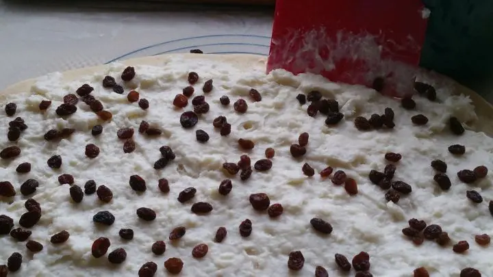 Nachdem er ausgewellt wurde, wird der Teig f&uuml;r die Puddingschnecken mit dem erkalteten Pudding bestrichen und mit Rosinen bestreut. 