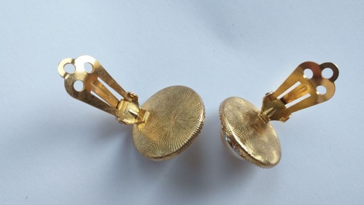 Zwei goldene Ohrclips liegen nebeneinander auf einem hellen Hintergrund und zeigen ihr elegantes Design f&uuml;r besseren Tragekomfort.