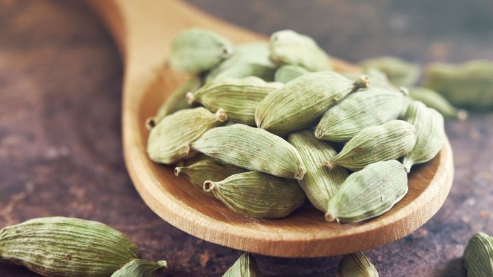 Gr&uuml;ne Kardamomkapseln liegen in einem Holzl&ouml;ffel, bereit zur Verwendung als nat&uuml;rlicher Mundgeruchkiller.