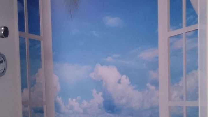 Ein Fenster mit Aussicht auf einen Strand wird digital dargestellt, um dem Badezimmer eine frische, mediterrane Note zu verleihen.
