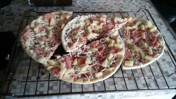 Auf einem Rost liegen zwei belegte Pizzen, die frisch gebacken sind und gut zusammenpassen.