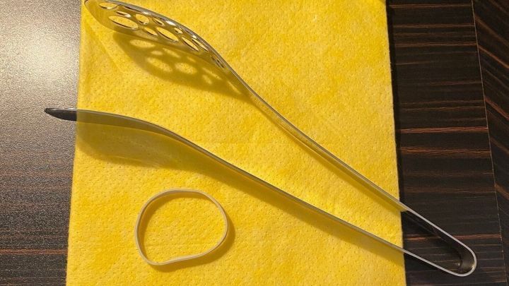 Ein Badheizk&ouml;rperreinigungstuch liegt zusammen mit einer Nudelzange und einem Gummiband auf einem Tisch.