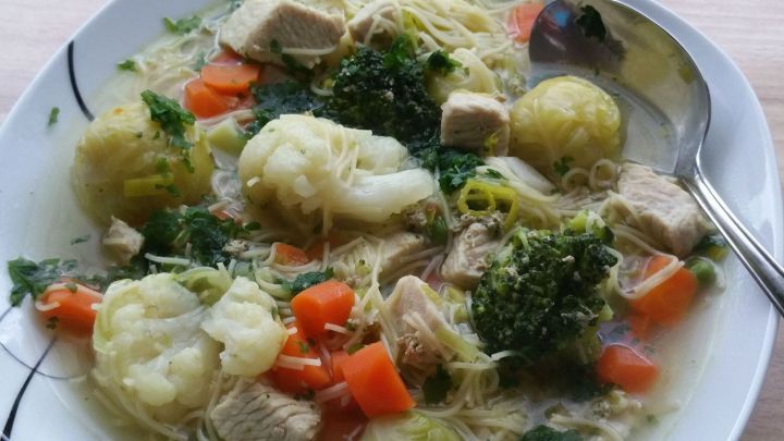 Eine Sch&uuml;ssel Nudel-Gem&uuml;sesuppe mit Putenbrust, gef&uuml;llt mit Gem&uuml;se und Fleisch, steht auf einem Tisch.
