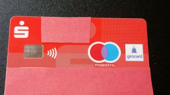 Eine rote Bankkarte liegt auf einer dunklen Oberfl&auml;che, bereit f&uuml;r kontaktloses Bezahlen und das sichere Verstecken der Geheimzahl.