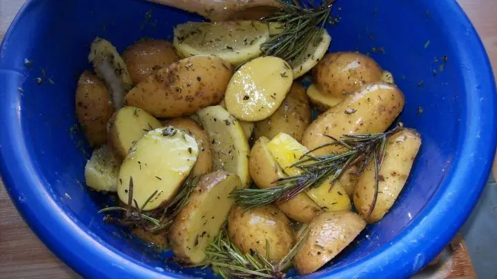 Die Kartoffelh&auml;lften und die restliche, mit der noch vorhandenen Schale auf Spalten geschnittene Zitrone werden nun zur Marinade in die Sch&uuml;ssel gegeben und gut durch gemengt. 