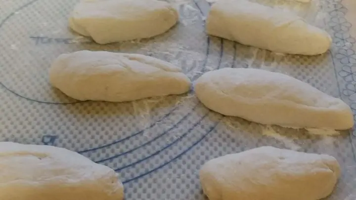 Von der Teigrolle 10 Teiglinge abstechen, einen davon rund schleifen, die restlichen 9 davon länglich formen.