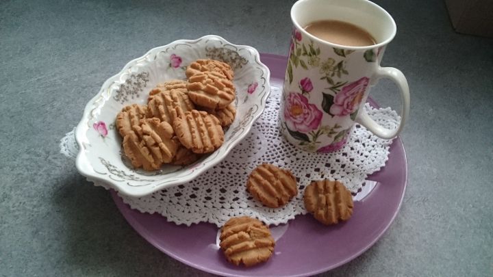 Kekse aus Sesampaste liegen auf einer Untertasse und werden mit einer Tasse Tee serviert, umgeben von einem dekorativen Teller.