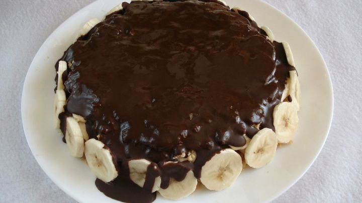 Eine schokoladige Torte mit Bananen-Sahne, auf einem wei&szlig;en Teller, pr&auml;sentiert in einem hellen, neutralen Umfeld.