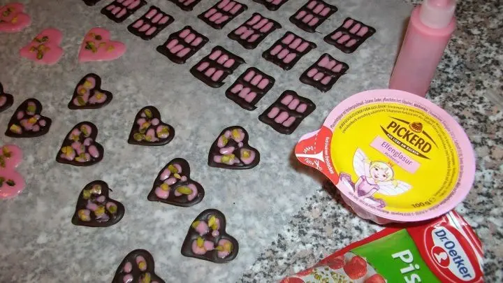 Ich selbst habe aus dunkler Kuvert&uuml;re und pinker Elfenglasur (schmeckt lecker nach Himbeere) kleine Herzchen mit Pistazienst&uuml;ckchen gebastelt. Da k&ouml;nnt ihr euch kreativ austoben.
