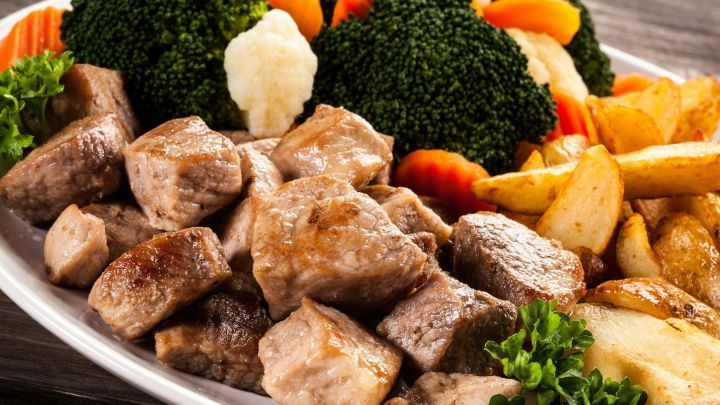 St&uuml;ckchen von zartem Gyros liegen auf einem Teller, umgeben von Brokkoli, M&ouml;hren und knusprigen Kartoffeln.