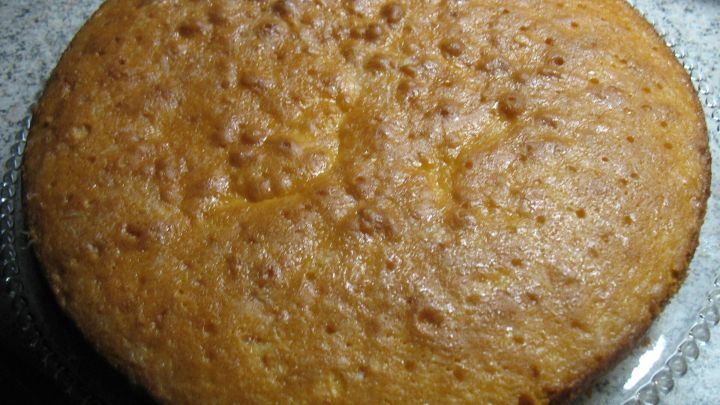 Eine saftige Zitronentorte liegt auf einer silbernen Platte und ist gleich zum Servieren bereit, umgeben von einer K&uuml;chenoberfl&auml;che.