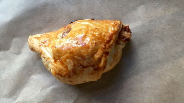 Ein goldbrauner Apfelstrudel-Biss liegt auf einem Backpapier, bereit zum Genie&szlig;en als schneller Snack.