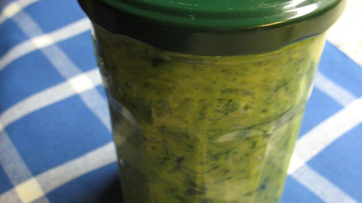 Ein Glas mit Zucchini-Rucola-Aufstrich steht auf einem blauen Karo-Tischtuch und wartet darauf, serviert zu werden.