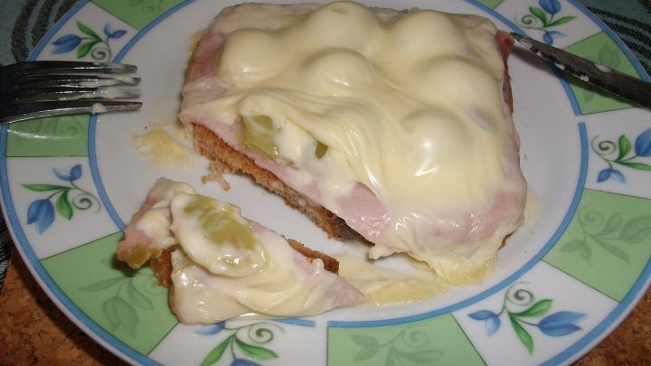 Auf einem Teller liegt ein Toast mit Schinken und Rosenkohl, &uuml;berzogen mit einer cremigen So&szlig;e, die schmilzt.