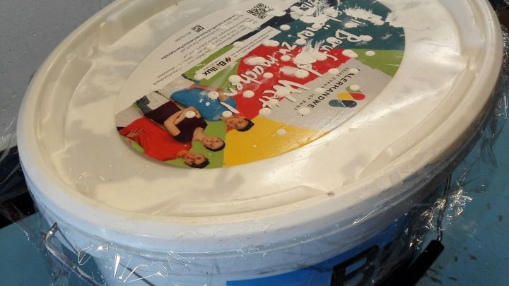 Ein Eimer mit Farbdeckung ruht auf einem Tisch, bereit zur richtigen Lagerung f&uuml;r Wandfarbe.