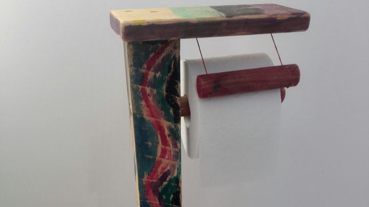 Ein farbenfroher Toilettenpapierhalter steht auf einem fliesenboden, bereit, Toilettenpapier zu bieten und zu nutzen.