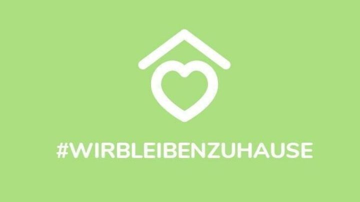 Ein Herz innerhalb eines Haus-Symbols symbolisiert das Zuhause. Dar&uuml;ber steht der Text: #WIRBLEIBENZuhause.