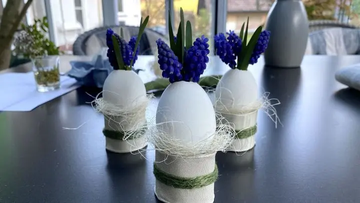 Leere Klopapierrollen k&ouml;nnen mit einer Schere zugeschnitten und zu Eierbechern umfunktioniert werden. Dekoiert mit Geschenkband und etwas Sisalgras passen sie perfekt zu den Eierv&auml;schen.