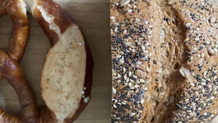 Ein frisches, knackiges Brot und eine weiche Brezel liegen auf einem Holzbrett, um genie&szlig;bar gemacht zu werden.