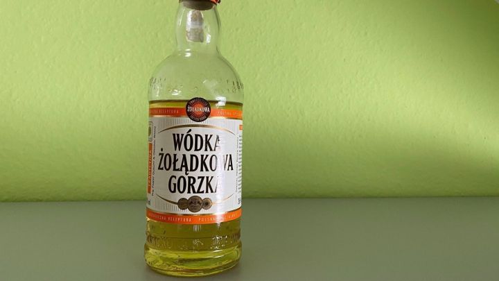 Eine Flasche Wodka steht auf einem Tisch vor einer gr&uuml;nen Wand, bereit zur Verwendung als Glasreiniger.