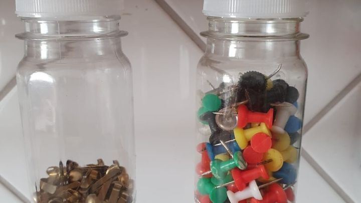 Zwei durchscheinende Beh&auml;lter h&auml;ngen unter einem Regal, einer f&uuml;r kleine Schrauben, der andere f&uuml;r bunten Stecknadeln.