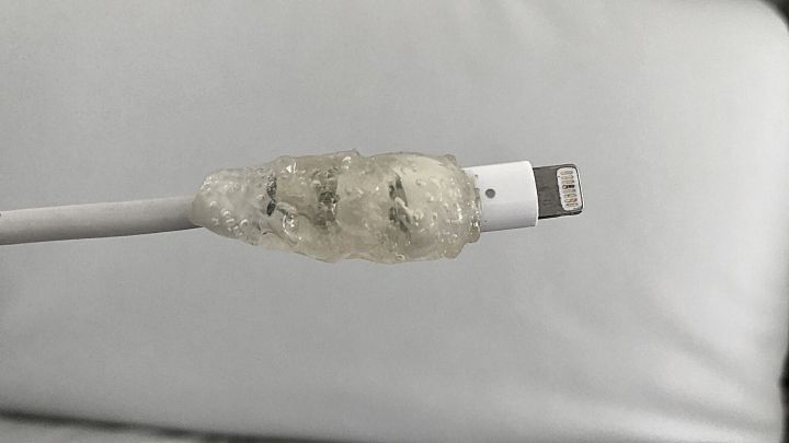 Ein Kabel mit einem klebrigen Schutz aus Klebstoff ist auf einem hellen Sofa platziert, um Sch&auml;den zu vermeiden.