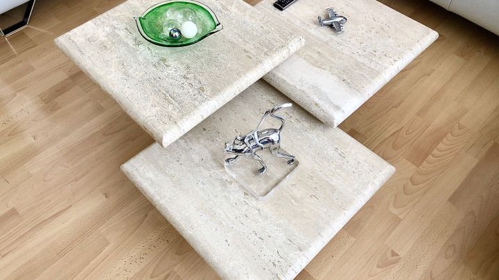 Ein eleganter Naturstein-Tisch mit drei Platten zeigt Kunstobjekte und eine gr&uuml;ne Schale, perfekt im Wohnraum platziert.