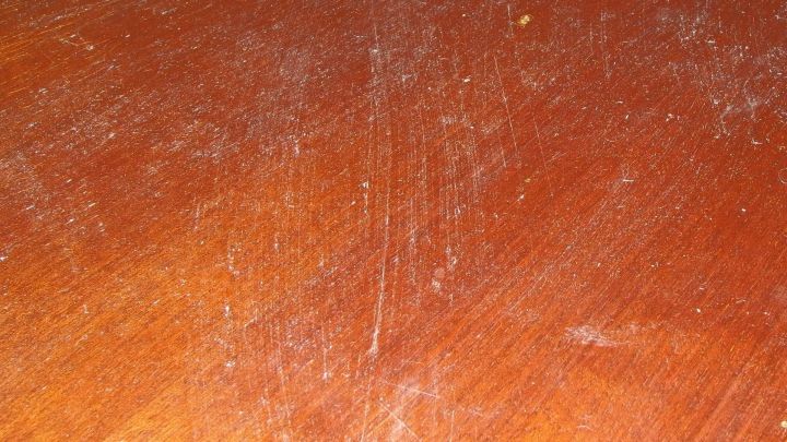 Eine Holzoberfl&auml;che mit sichtbaren Kratzern und Staub, die darauf wartet, keimfrei gemacht zu werden.