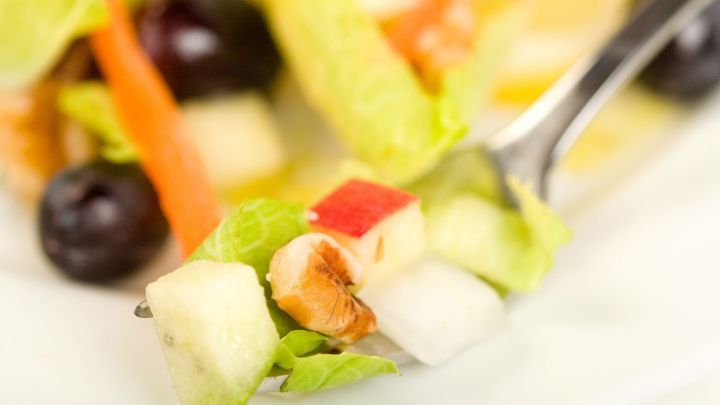 Ein frischer Chicoreesalat liegt auf einer Gabel, gemischt mit bunten Zutaten wie &Auml;pfeln, Trauben und Karotten.